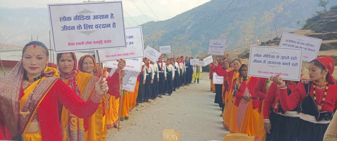Women line a village road holding community-awareness placards.