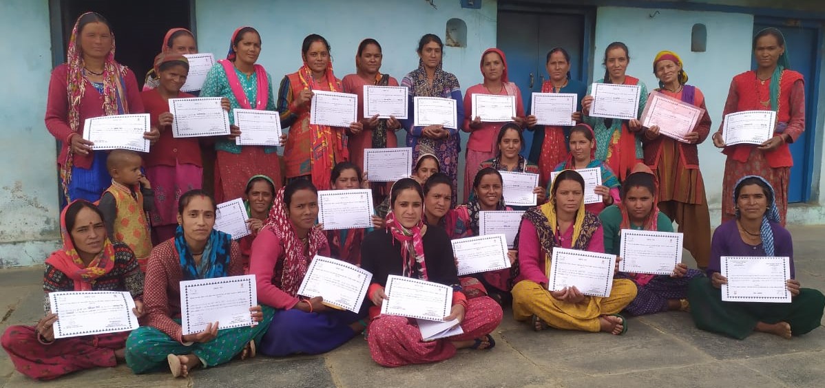 Women display their certificates together after a community programme.
