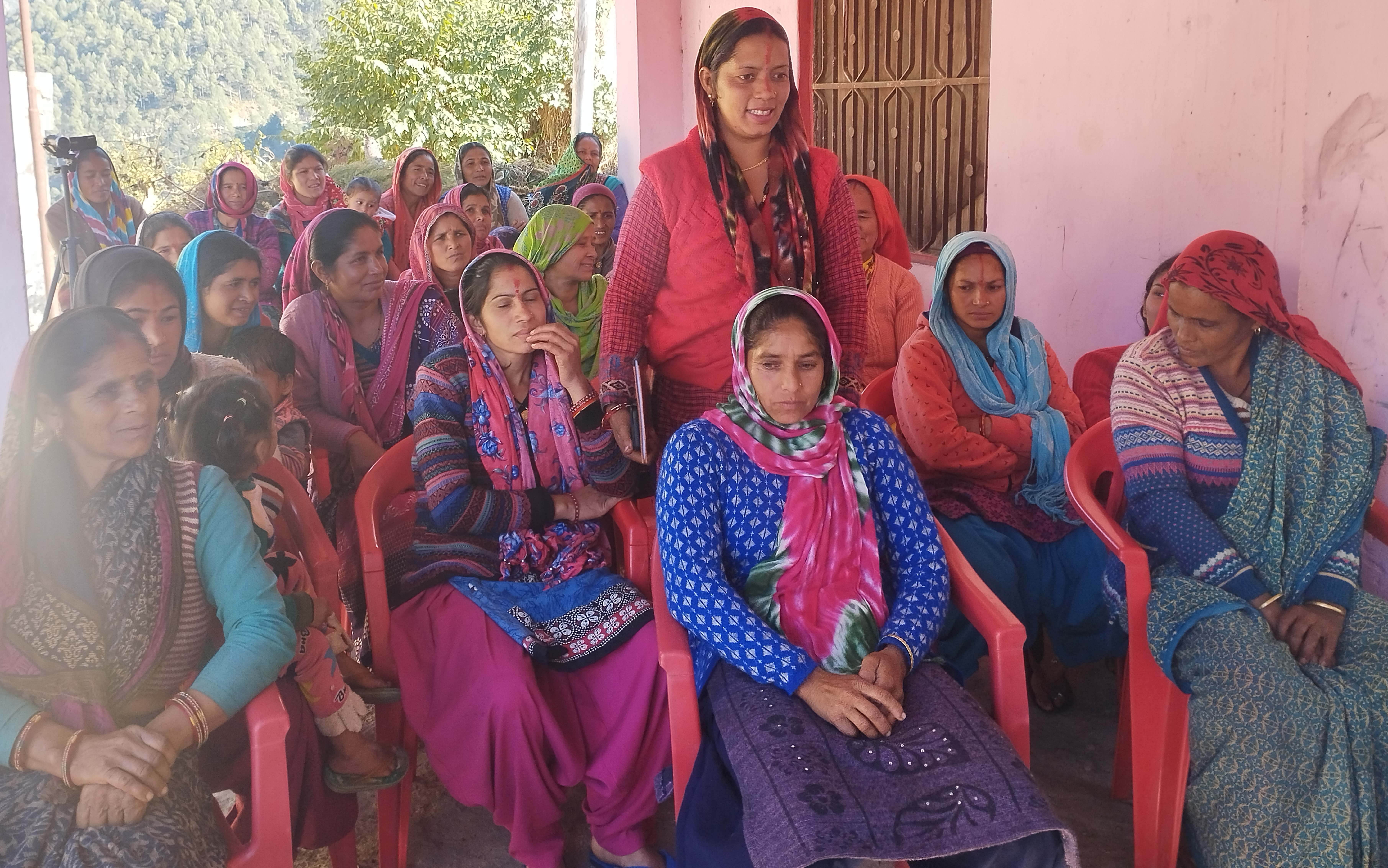 A woman addresses fellow participants during a seated community workshop.