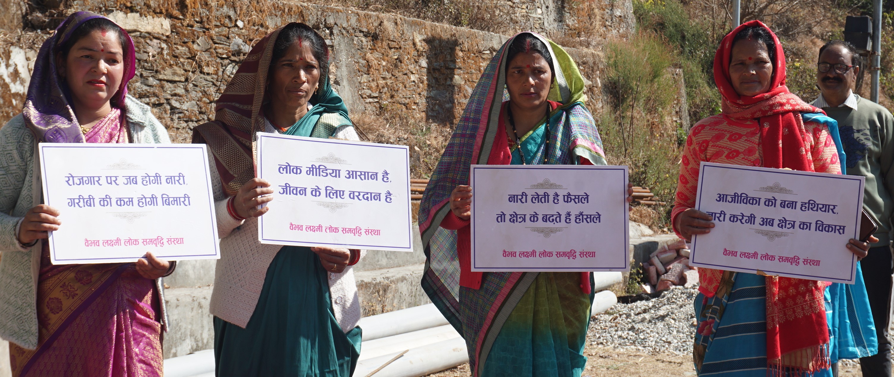Women hold placards about livelihoods, folk media, and women’s participation at Kaflodi.