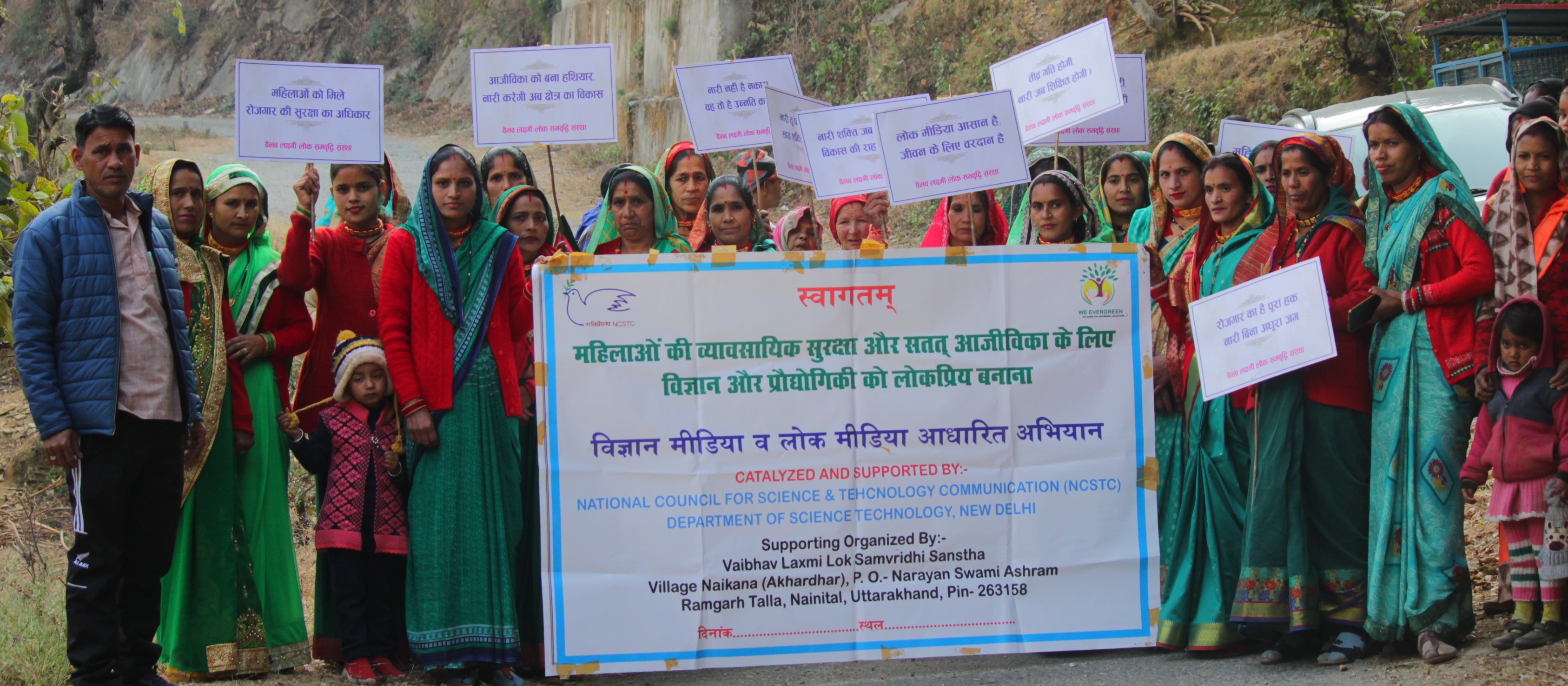 Women hold awareness placards behind a community programme banner at Mtyala.