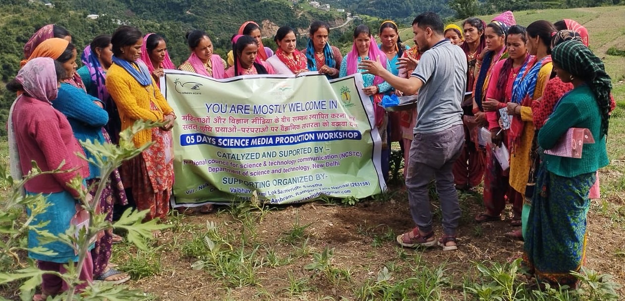 Women and organizers gather in a green field with a VLLSS video consultation banner.
